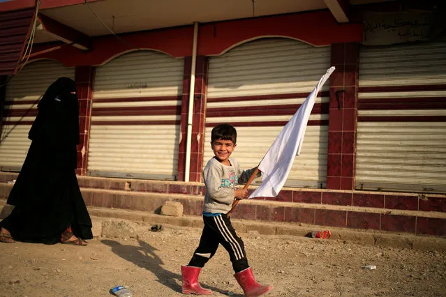 A boy, who is fleeing the fighting between Islamic State and Iraqi army in Mosul, smiles as he with a white flag in Samah district, eastern Mosul, Iraq November 12, 2016. (Photo by Zohra Bensemra/Reuters)