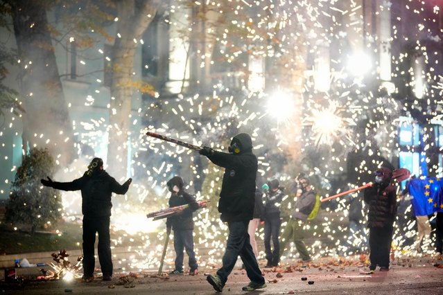 Demonstrators launch firecrackers during a protest against the government's decision to suspend negotiations on joining the European Union in Tbilisi, Georgia, early Wednesday, December 4, 2024. (Photo by Pavel Bednyakov/AP Photo)