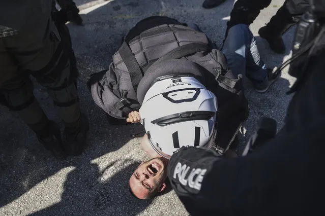Police detain a protester at the University of Thessaloniki in northern Greece, on Monday, February 22, 2021. Police clashed with protesters and detained more than 30 people in Greece's second-largest city Monday during a demonstration against a new campus security law. (Photo by Giannis Papanikos/AP Photo)