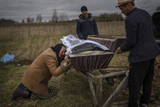 Nadiya Trubchaninova, 70, cries while holding the coffin of her son Vadym, 48, who was killed by Russian soldiers last March 30 in Bucha, during his funeral in the cemetery of Mykulychi, on the outskirts of Kyiv, Ukraine, Saturday, April 16, 2022. After nine days since the discovery of Vadym's body, finally Nadiya could have a proper funeral for him. (Photo by Rodrigo Abd/AP Photo)