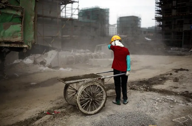 Ou Mei, a 45-year-old female migrant construction worker, shields her face from dust during a shift at a residential construction site in Shanghai in this July 2, 2013 file photo. China's slowing economy is making it harder for Beijing to mend holes in its pension system for the country's 268 million migrant workers. (Photo by Aly Song/Reuters)