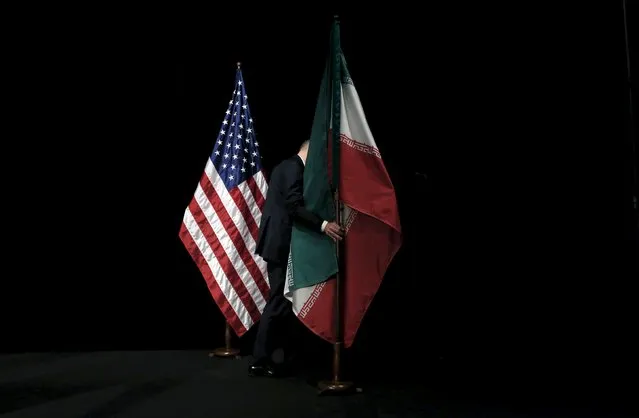 A staff member removes the Iranian flag from the stage after a group picture during the Iran nuclear talks at the Vienna International Center in Vienna, Austria July 14, 2015. (Photo by Carlos Barria/Reuters)