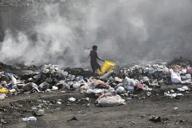A woman walks through a landfill looking for salvageable items, in Port-au-Prince, Haiti, Saturday, July 1, 2023. (Photo by Joseph Odelyn/AP Photo)