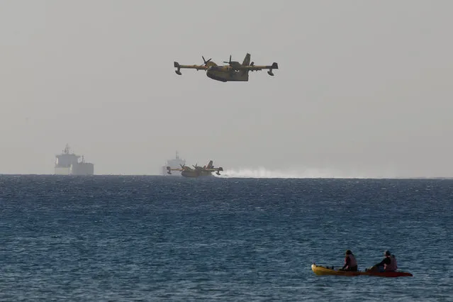 People look on as Greek firefighting planes collect water from the Mediterranean sea in Acre as they help to fight wildfire over northern Israel November 25, 2016. (Photo by Baz Ratner/Reuters)