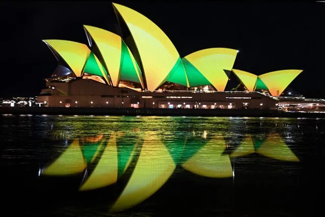 The Sydney Opera House is illuminated in green and gold in Sydney on August 7, 2023, to support the Australia's women's football team ahead of their first World Cup knock-out round match against Denmark. (Photo by Muhammad Farooq/AFP Photo)