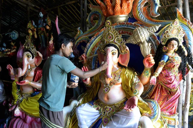 An Indian artist gives final touches to an eco- friendly figure of the Hindu deity Ganesh at a workshop in Hyderabad on September 11, 2018, ahead of the upcoming Ganesh Chaturthi celebrations on September 13. The eco- friendly Ganesh idols are made with mud, jute fiber and bamboo, and are aimed at reducing pollution during the Ganesh immersion rituals. (Photo by Noah Seelam/AFP Photo)