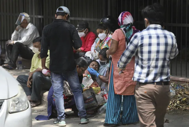 A woman comforts her relative as they wait to receive the body of a person who died of COVID-19 outside a mortuary, in New Delhi, India, Monday, April 19, 2021. New Delhi imposed a weeklong lockdown Monday night to prevent the collapse of the Indian capital's health system, which authorities said had been pushed to its limit amid an explosive surge in coronavirus cases. (Photo by Manish Swarup/AP Photo)