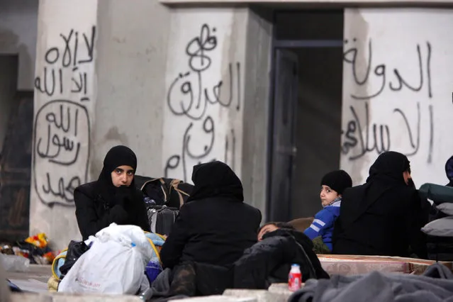 Syrians evacuated from eastern Aleppo, rest inside a shelter in government controlled Jibreen area in Aleppo, Syria December 1, 2016. Writings on the wall read in Arabic, “There is no god but Allah and Mohamad is his prophet” (L) and “Islamic State in Iraq and the Levant” (R, centre). (Photo by Omar Sanadiki/Reuters)