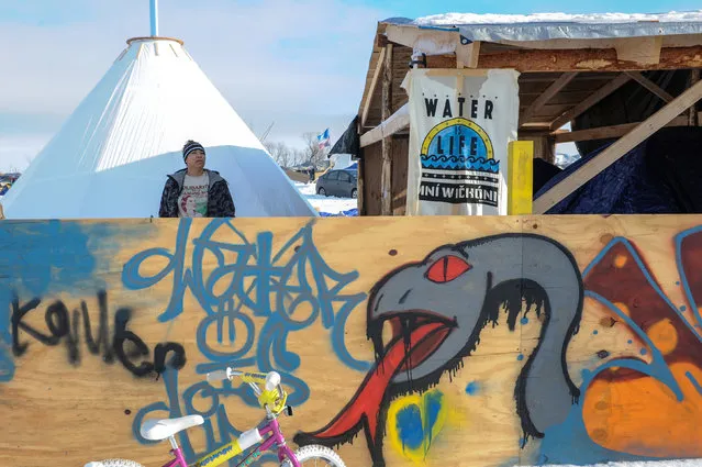A woman stands in a camp behind graffiti of a black snake in Oceti Sakowin camp as “water protectors” continue to demonstrate against plans to pass the Dakota Access pipeline near the Standing Rock Indian Reservation, near Cannon Ball, North Dakota, U.S. December 3, 2016. (Photo by Stephanie Keith/Reuters)