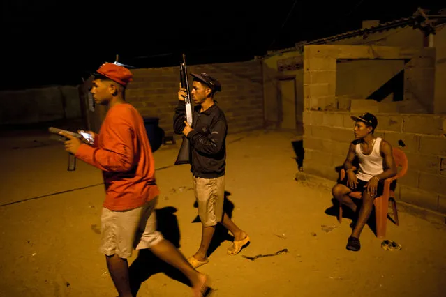 In this November 2, 2016 photo, members of the Marval family, who patrol at night while other members of their family fish at sea, respond to what appeared to be the start of an attack by pirate gang leader “El Beta” in Punta de Araya, Sucre state, Venezuela. The family says El Beta is a 19-year-old killer with 40 men at his command who threatened to kill their entire clan days after murdering three Marvals at sea and stealing their night's catch. (Photo by Rodrigo Abd/AP Photo)