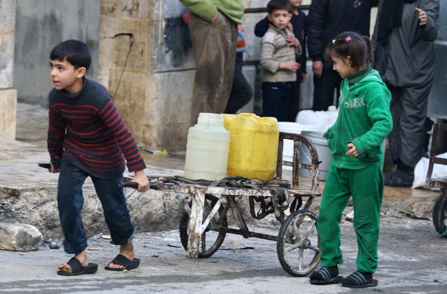 A boy pushes a cart with water containers in a rebel-held besieged area of Aleppo, Syria December 10, 2016. (Photo by Abdalrhman Ismail/Reuters)
