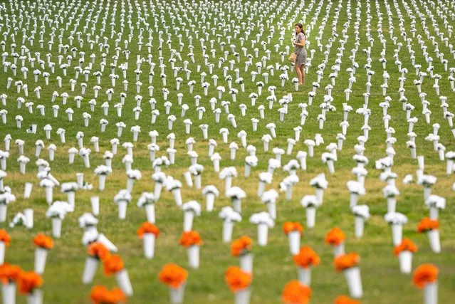 Jordan Costa, Giffords community violence initiative project manager, walks through a field of flowers representing deaths from gun violence at the Giffords Gun Violence Memorial in front of the Washington Monument on June 7, 2022 in Washington, DC. Activists and congressional leaders spoke about a renewed push for gun control legislation Monday in the wake of a series of high-profile U.S. shootings. (Photo by Nathan Howard/Getty Images)
