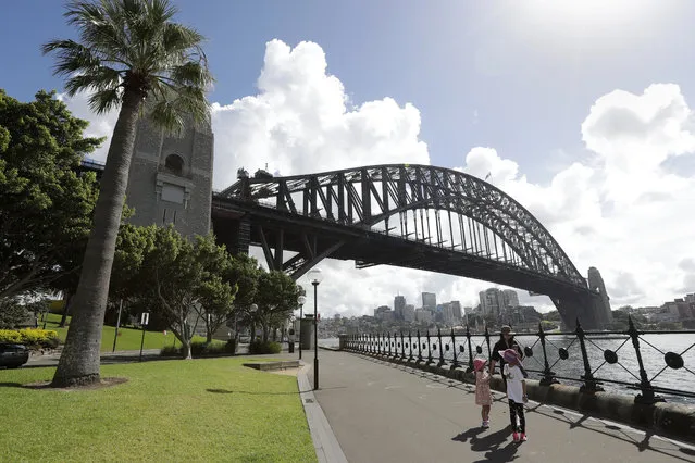 A woman and 2 children walk under the Harbour Bridge in a popular area in Sydney, Australia, Tuesday, April 6, 2021. (Photo by Rick Rycroft/AP Photo)