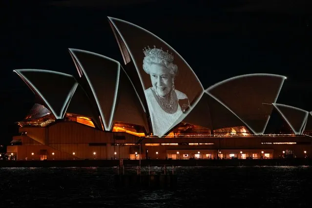 The Sydney Opera House is illuminated with a portrait of Queen Elizabeth II in Sydney, Australia, Friday, September 9, 2022. Queen Elizabeth II, Britain's longest-reigning monarch and a rock of stability in a turbulent era for her country and the world, died Thursday, Sept. 8 after 70 years on the throne. She was 96. (Photo by Mark Baker/AP Photo)