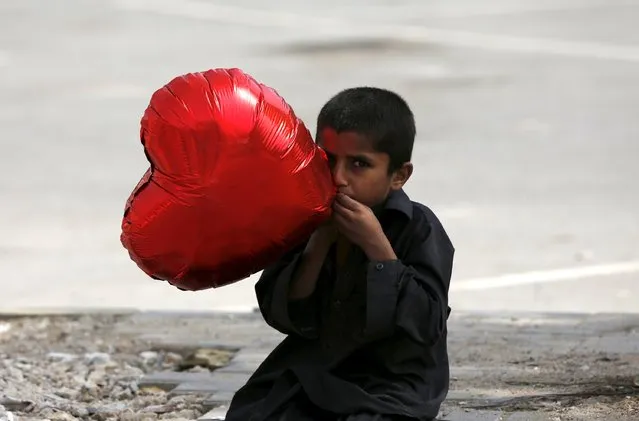  A boy inflates a heart-shaped balloon to sell on Valentine's Day in Karachi, Pakistan February 14, 2016. (Photo by Akhtar Soomro/Reuters)