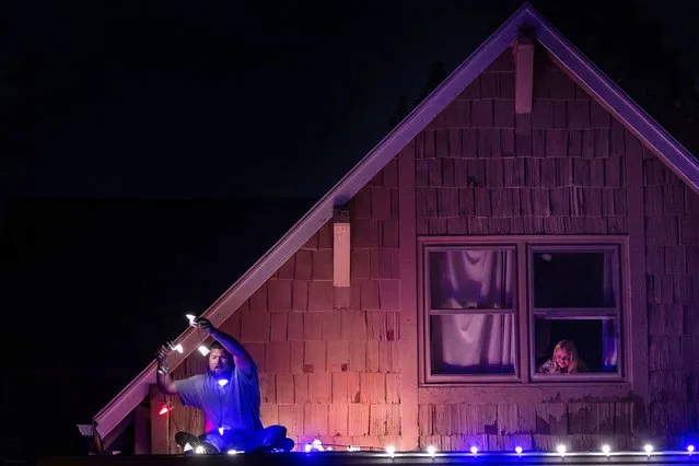 Justin Holzepfel puts Christmas lights on his roof in Omaha, Nebraska, as his 5-year-old daughter, Madalyn, watches on Tuesday, November 14, 2023. (Photo by Chris Machian/Omaha World-Herald via AP Photo)