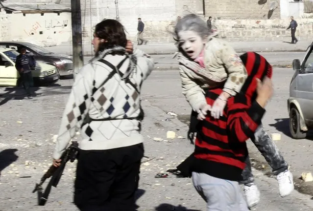A man carries a wounded girl who survived what activists say was an air strike by forces loyal to Syrian President Bashar al-Assad in Aleppo's al-Ansari al-Sharqi neighborhood, December 9, 2013. (Photo by Ammar Abdullah/Reuters)