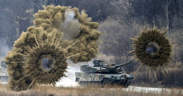 Smoke bombs explode near a South Korean army K-2 tank during a live firing drill at a fire training field in Yangpyeong, South Korea, Thursday, February 18, 2016. North Korean leader Kim Jong Un recently ordered preparations for launching “terror” attacks on South Koreans, a top Seoul official said Thursday, as worries about the North grow after its recent nuclear test and rocket launch. (Photo by Lim Hun-jung/Yonhap via AP Photo)