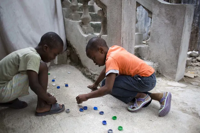 In this January 8, 2017 photo, Judeley Hans Debel, right, who's right leg is a prosthesis, plays bottle cap soccer with a neighbor at his home in Petion-Ville, Haiti. Just 2 ½ years old at the time, Judeley's tiny body was pinned under earthquake rubble at his shattered concrete home in 2010. His mother dug him out and rushed him to a hospital where his leg was amputated. (Photo by Dieu Nalio Chery/AP Photo)