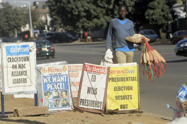 A vendor sells sponges near newspaper headlines on the streets of Harare, Friday, August 3, 2018. Zimbabwe's President Emmerson Mnangagwa won an election Friday with just over 50 percent of the ballots as the ruling party maintained control of the government in the first vote since the fall of longtime leader Robert Mugabe. (Photo by Tsvangirayi Mukwazhi/AP Photo)