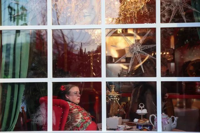 A woman looks from a window of a pavilion at a New Year and Christmas fair in downtown Moscow on January 2, 2024. (Photo by Vera Savina/AFP Photo)
