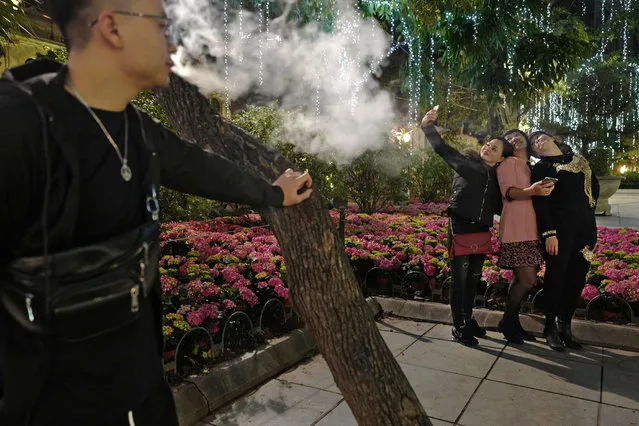 In this Saturday, February 23, 2019, photo, women pose for a selfie while a man smokes at a peak near Hoan Kiem Lake in Hanoi, Vietnam. As Vietnam’s capital gears up for the second summit between U.S. President Donald Trump and North Korean leader Kim Jong Un, people take time to relax at nighttime by Hoan Kiem Lake in downtown Hanoi. (Photo by Vincent Yu/AP Photo)