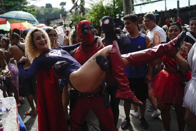 A reveler wearing a Deadpool costume carries a woman in a Super Woman costume as they enjoy the Carmelitas street party in Rio de Janeiro, Brazil, Friday, March 1, 2019. Much of the appeal of Rio street parties is the variety of themes and that people can dress up in costumes or not. (Photo by Leo Correa/AP Photo)