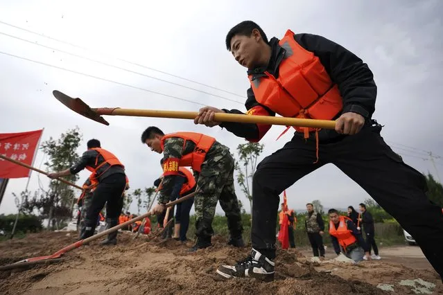 In this photo released by Xinhua News Agency, rescuer workers fortify a temporary dyke against the flooding at the Lianbo Village in Hejin City, in northern China's Shanxi Province, Sunday, October 10, 2021. (Photo by Zhan Yan/Xinhua via AP Photo)