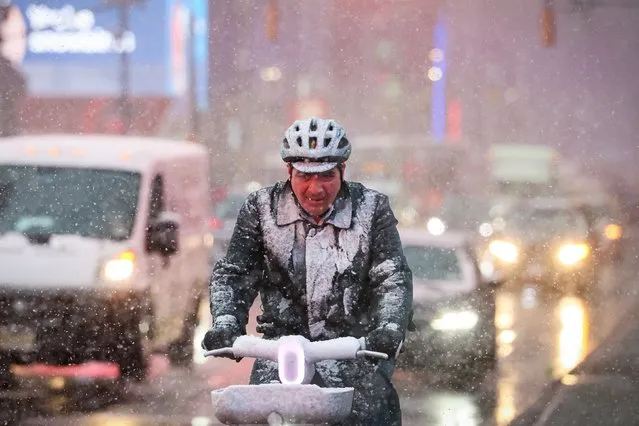 A man rides a bicycle during the morning commute through wind and snow during a Nor'easter winter storm in Times Square in New York City, U.S., February 13, 2024. (Photo by Brendan McDermid/Reuters)