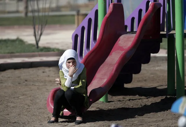A Syrian refugee girl sits at a playground at the Oncupinar refugee camp for Syrian refugees next to the border crossing with Syria, near the town of Kilis in southeastern Turkey, Thursday, March 17, 2016. The European Union and Turkey hope to reach a comprehensive deal this week to tackle illegal migration and the refugee crisis spurred by conflicts in Syria and beyond. In return for its efforts, Turkey stands to gain $3.3 billion in EU funding to help it improve the situation of the 2.7 million Syrian refugees already within its borders. (Photo by Lefteris Pitarakis/AP Photo)
