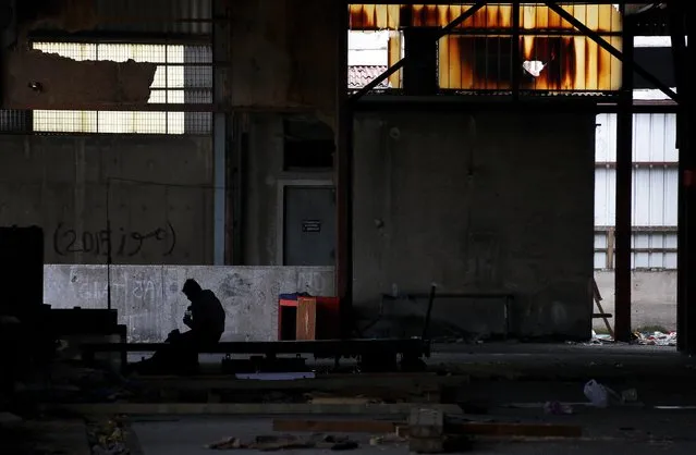 An Afghan immigrant is sits inside a wood factory across the street from a ferry terminal in the western Greek town of Patras April 28, 2015. (Photo by Yannis Behrakis/Reuters)