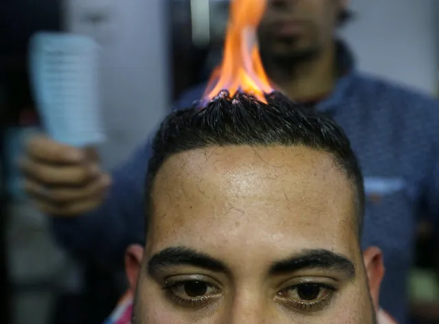 Palestinian barber Ramadan Odwan styles and straightens the hair of a customer with fire at his salon in Rafah, in the southern Gaza Strip February 2, 2017. (Photo by Ibraheem Abu Mustafa/Reuters)