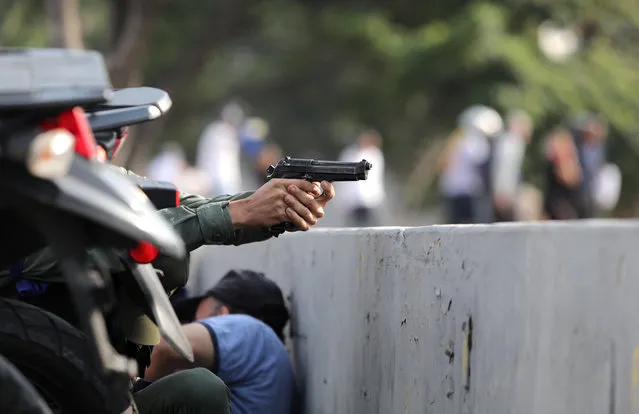 A military member aims a gun near the Generalisimo Francisco de Miranda Airbase “La Carlota”, in Caracas, Venezuela April 30, 2019. (Photo by Manaure Quintero/Reuters)