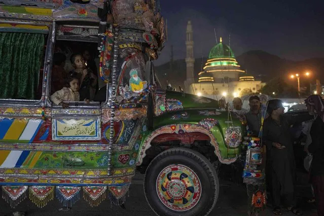 Two girls look out of a traditional bus with the Bari Imam shrine in the background, in Islamabad, Pakistan, Thursday, November 11, 2021. (Photo by Petros Giannakouris/AP Photo)