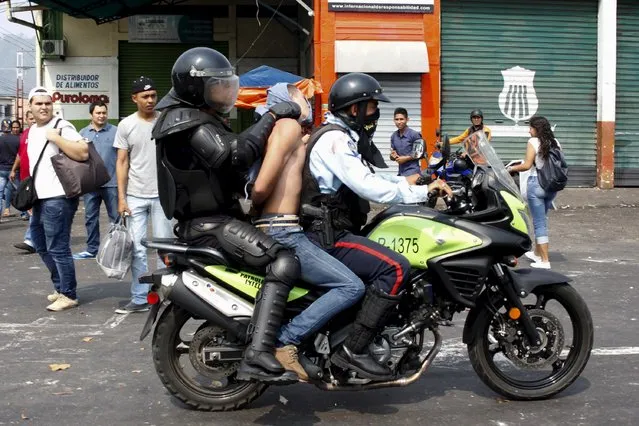 Police officers detain a demonstrator (C) on a motorcycle during a protest against the increase in the price of public transport in San Cristobal March 29, 2016. (Photo by Carlos Eduardo Ramirez/Reuters)