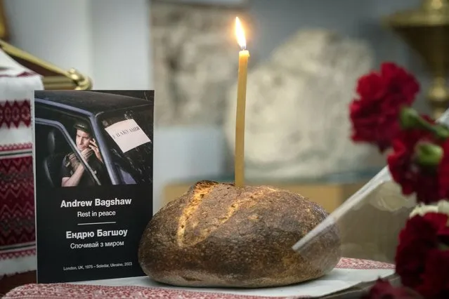 A church candle in a loaf of bread near a photo of Andrew Bagshaw, a British volunteer killed in Ukraine's war-hit east, during commemorating service in a refectory near St. Sophia Cathedral in Kyiv, Ukraine, Sunday, January 29, 2023. Andrew Bagshaw was a dual New Zealand and British citizen who was killed along with British colleague Chris Parry while attempting to rescue an elderly woman from the town of Soledar when their car was hit by an artillery shell. (Photo by Efrem Lukatsky/AP Photo)