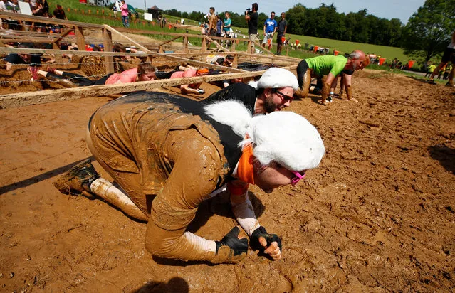 Participant dressed as late German fashion designer Karl Lagerfeld crawl through an obstacle called “kiss of mud” during the Tough Mudder untimed hardcore endurance event in Arnsberg, Germany on June 1, 2019. (Photo by Wolfgang Rattay/Reuters)