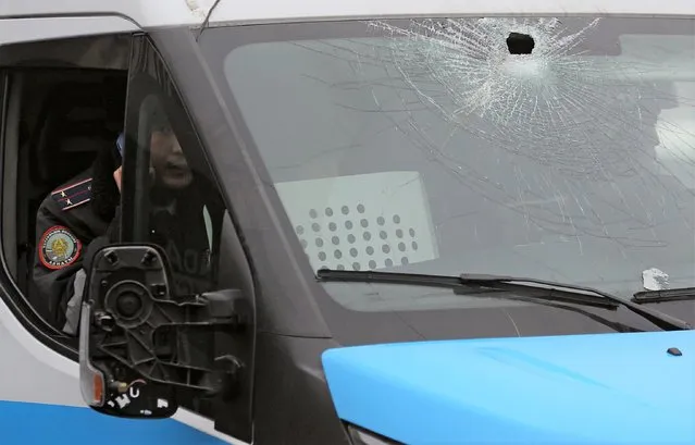 A Kazakh police officer sits inside a police van with a broken window during a protest triggered by fuel price increase in Almaty, Kazakhstan on January 5, 2022. (Photo by Pavel Mikheyev/Reuters)