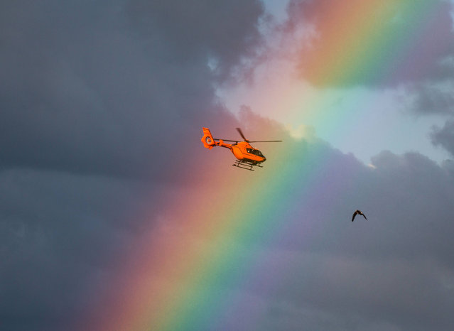 In this Sunday, June 26, 2016 photo a rescue helicopter that just took off from the roof of an accident hospital flies in front of a rainbow in the evening sky above the city in Frankfurt am Main, Germany. (Photo by Frank Rumpenhorst/DPA via AP Photo)