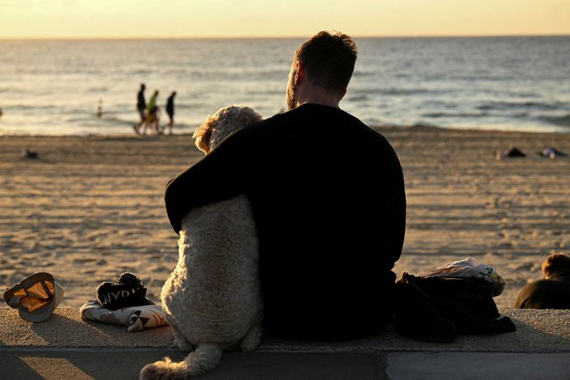 A man wraps his arm around a dog on ANZAC Day at Coogee Beach in Sydney, Australia, on April 25, 2024. (Photo by Jaimi Joy/Reuters)