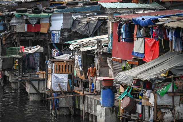 A man walks along makeshift homes in Manila on April 23, 2024. (Photo by Jam Sta Rosa/AFP Photo)