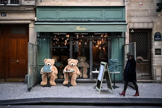 A woman walks in front of teddy bears displayed on the terrace of a closed restaurant in Paris on March 20, 2021, on the first day of a new lockdown in France aimed to curb the spread of the Covid-19 cases. Several parts of France enter a new partial lockdown. The new restrictions apply to around a third of the country's population affecting, Paris and several regions in the north and south. Schools are staying open. (Photo by Anne-Christine Poujoulat/AFP Photo)