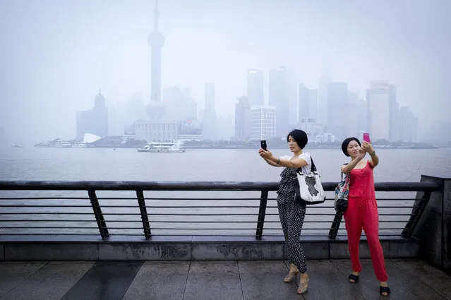 “Chinese tourists”. Two ladies take pictures of themselves with their cellphones in front of the skyline of Lujiazui, Pudong. Photo location: Shanghai, China. (Photo and caption by Jian Gao/National Geographic Photo Contest)