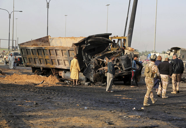 Iraqi security forces and civilians inspect the aftermath of a deadly suicide bombing in southern Baghdad, Iraq, Thursday, March 30, 2017. A suicide truck bomb targeted a police checkpoint in southern Baghdad on Wednesday night, killing and wounding scores according to Iraqi officials. (Photo by Karim Kadim/AP Photo)