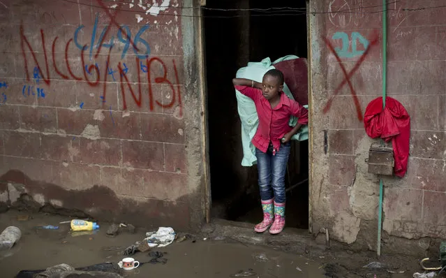 A young girl carries some of her family's belongings, as she and others are evicted from their apartment blocks close to the site of last week's building collapse, after their homes were deemed unfit for habitation and marked with a red “X” for demolition, in the Huruma neighborhood of Nairobi, Kenya Friday, May 6, 2016. (Photo by Ben Curtis/AP Photo)