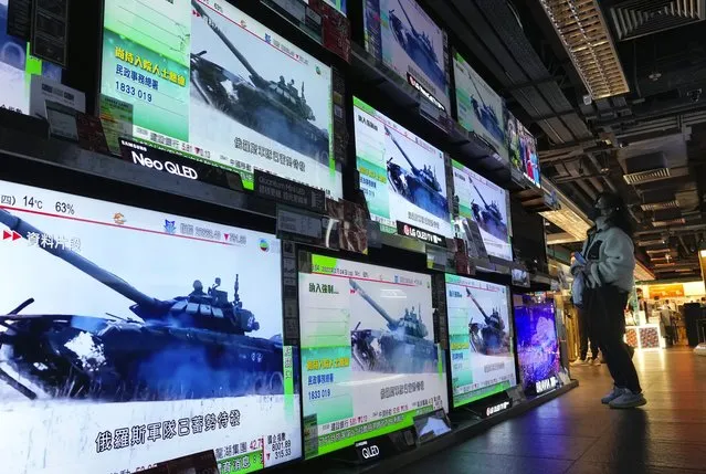 A woman stands in front of TV screens broadcasting the news of Russian troops that launched their attack on Ukraine, in Hong Kong Thursday, February 24, 2022. Russian troops launched their anticipated attack on Ukraine on Thursday, as President Vladimir Putin cast aside international condemnation and sanctions, warning other countries that any attempt to interfere would lead to “consequences you have never seen”. (Photo by Vincent Yu/AP Photo)