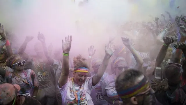 Runners frolic in a haze of colored powder in Sawyer Point Park during a color run as part of the All-Star Game festivities, Saturday, July 11, 2015, in Cincinnati. (Photo by John Minchillo/AP Photo)