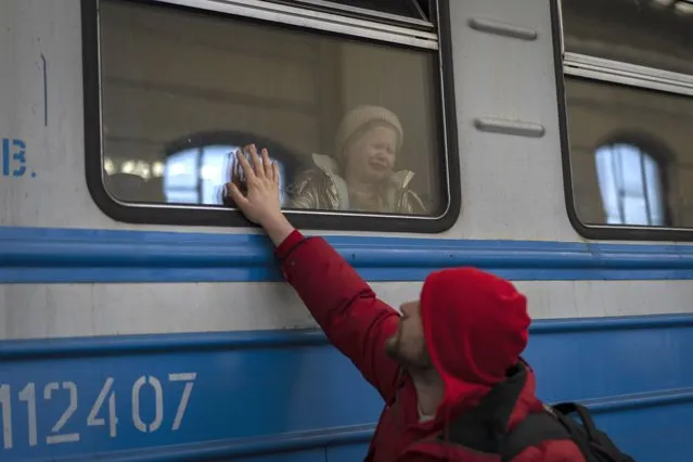 Displaced Ukrainians on a Poland-bound train bid farewell in Lviv, western Ukraine, Tuesday, March 22, 2022. The U.N. refugee agency says more than 3.5 million people have fled Ukraine since Russia's invasion, passing another milestone in an exodus that has led to Europe's worst refugee crisis since World War II. (Photo by Bernat Armangue/AP Photo)