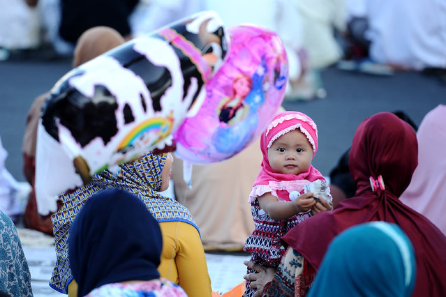 An Indonesian Muslims girl plays as the others perform Eid prayer on July 17, 2015 in Surabaya, Indonesia. Muslims worldwide observe the Eid Al-Fitr prayer to mark the end of Ramadan and the beginning of the new month of blessing Shawwal 1436 Hijriah. (Photo by Robertus Pudyanto/Getty Images)