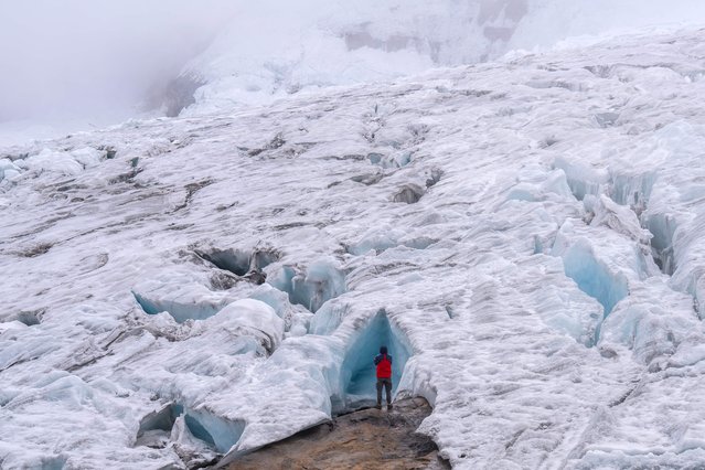 A tourist explores the Ritacuba Blanco glacier at the Natural National Park Nevado El Cocuy in Boyaca Department, Colombia, on April 19, 2024. The Ritacuba Blanco glacier, one of Colombia's highest snow-capped peaks, should be covered by a blanket of homogeneous snow. But a brutal El Niño phenomenon melted it and exposed gigantic crevasses, a sign of its agony. (Photo by Luis Acosta/AFP Photo)